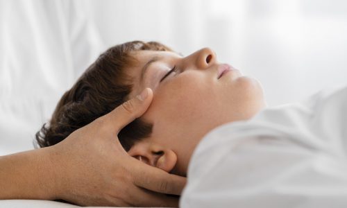 weibliche-osteopathin-die-ein-kind-behandelt-indem-sie-seinen-kopf-massiert